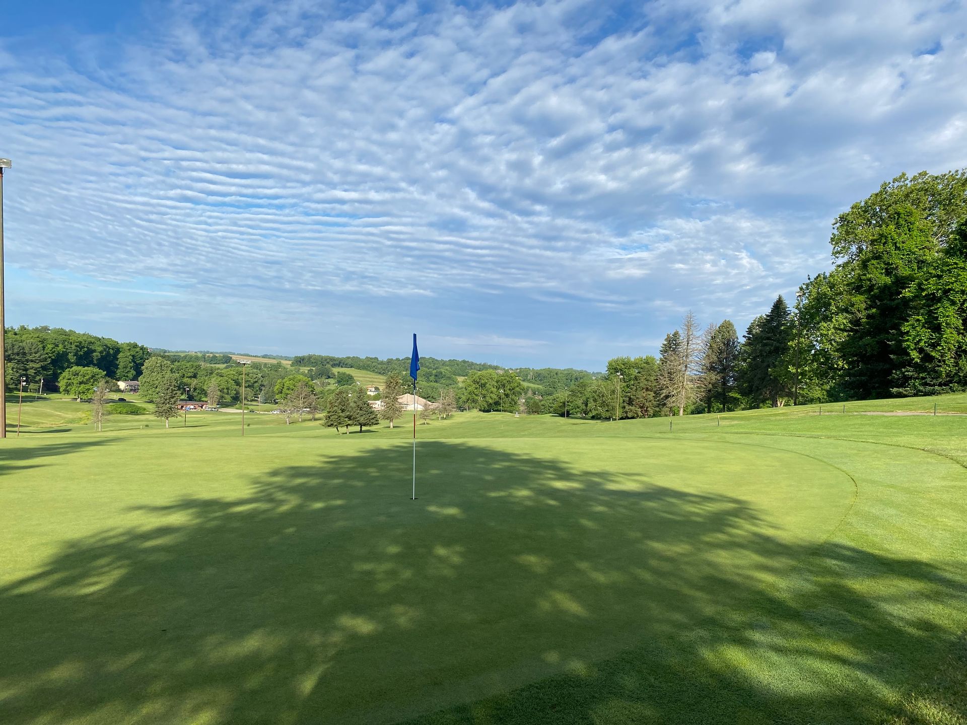 A golf course with a flag on the green and trees in the background