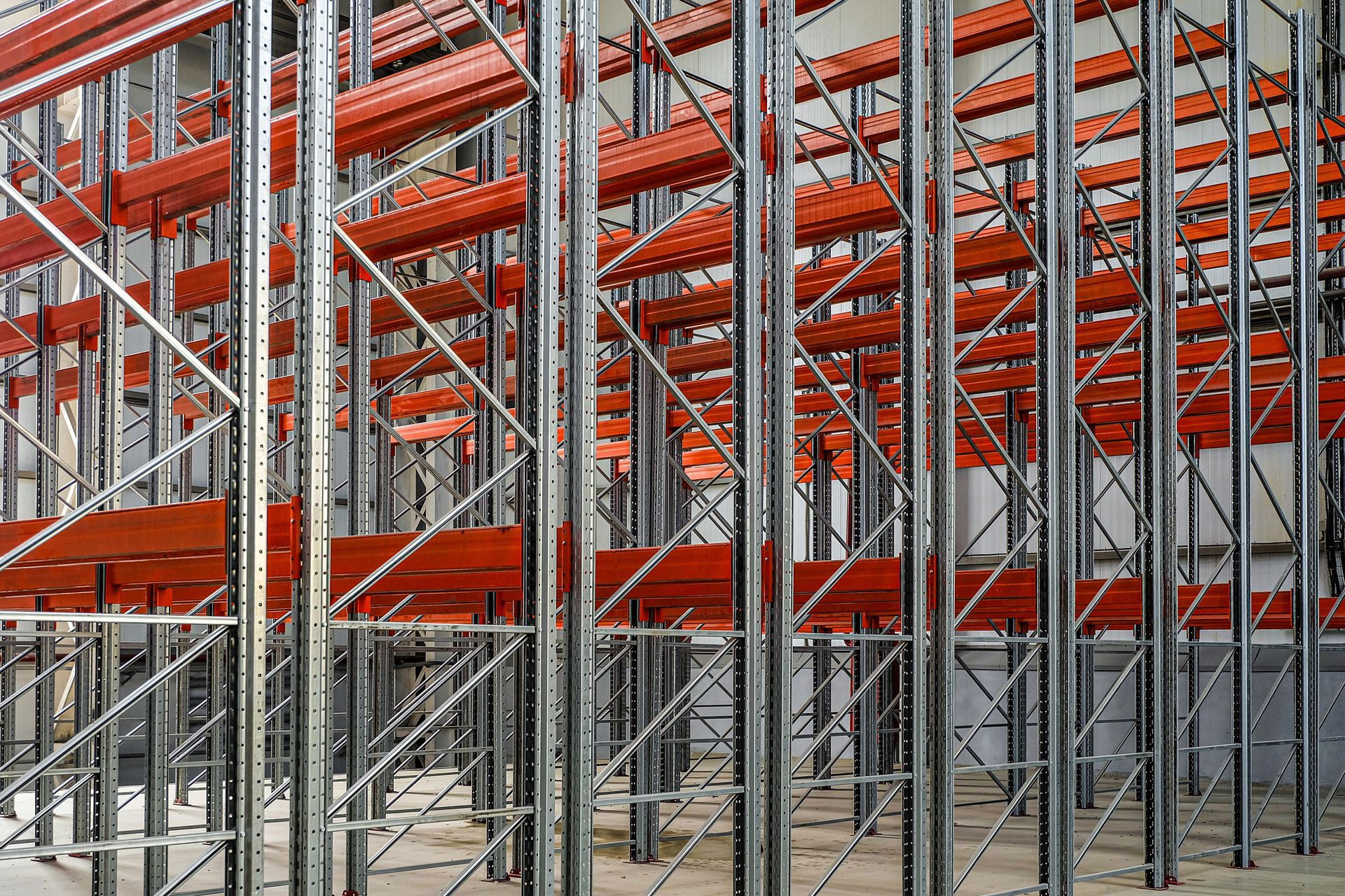 Warehouse racking system; steel and orange beams, empty, industrial interior.