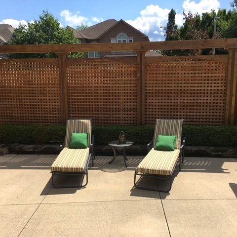 Two lounge chairs are sitting in front of a wooden fence