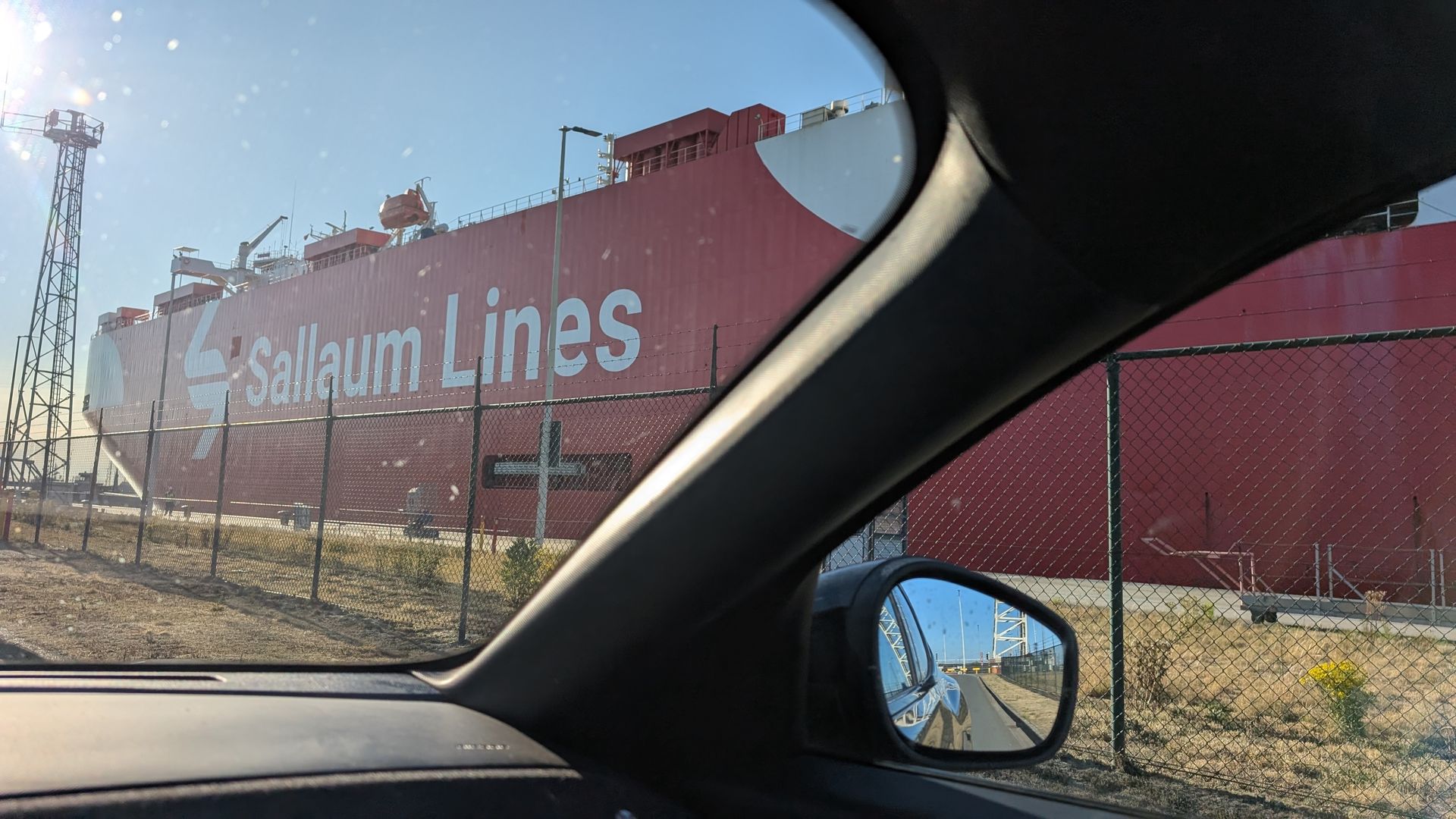 Uitzicht vanuit een auto op een groot rood vrachtschip van