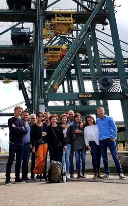Group of people posing in front of large port cranes.