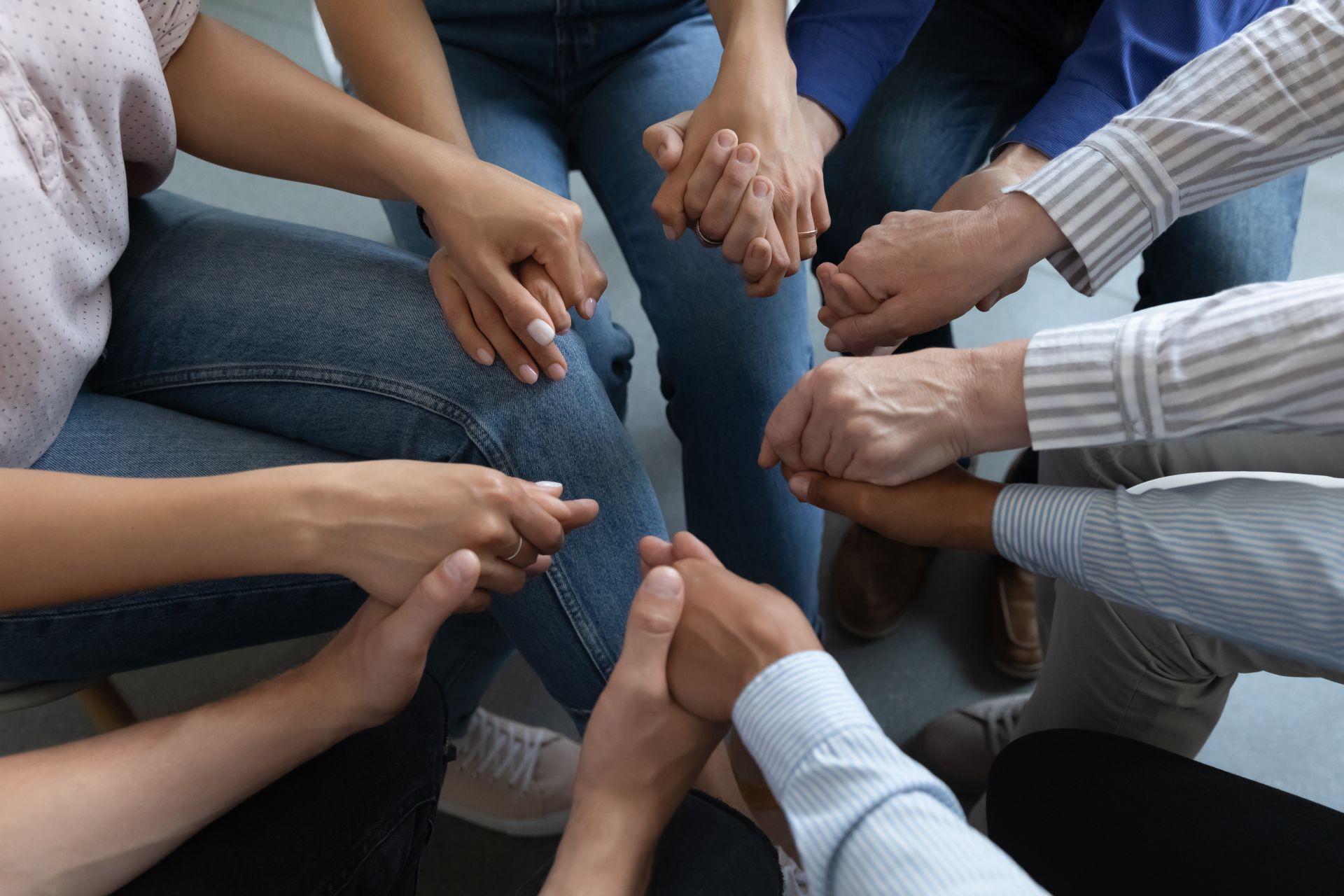 People holding hands in a circle; group therapy session.