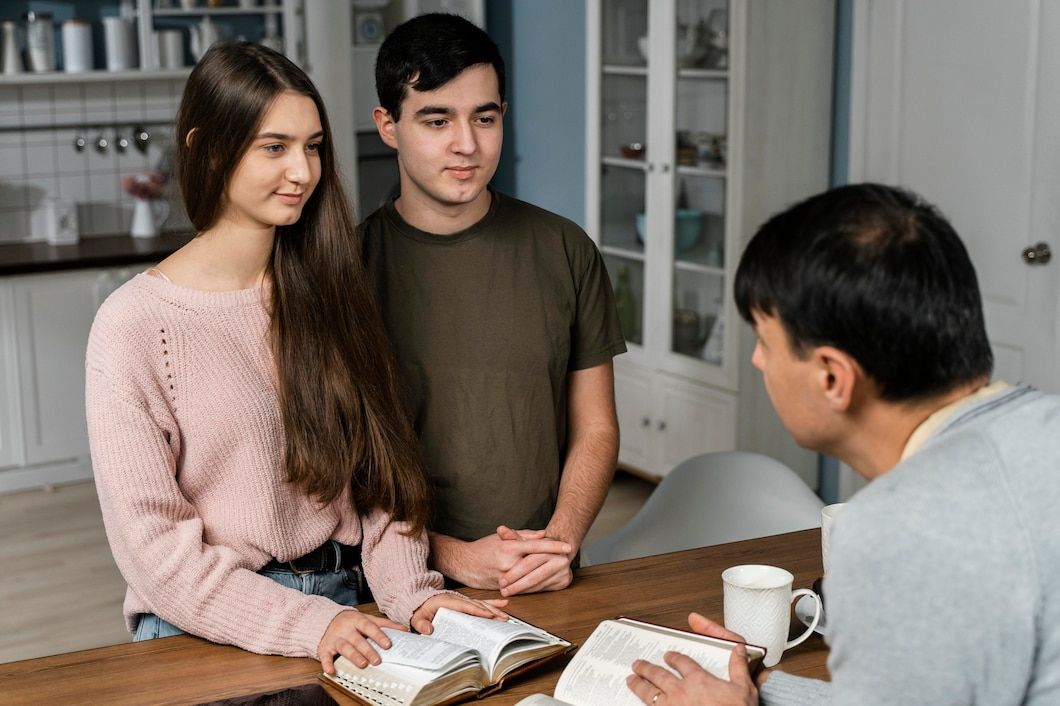 Couple in therapy, smiling, holding hands, counselor in background.