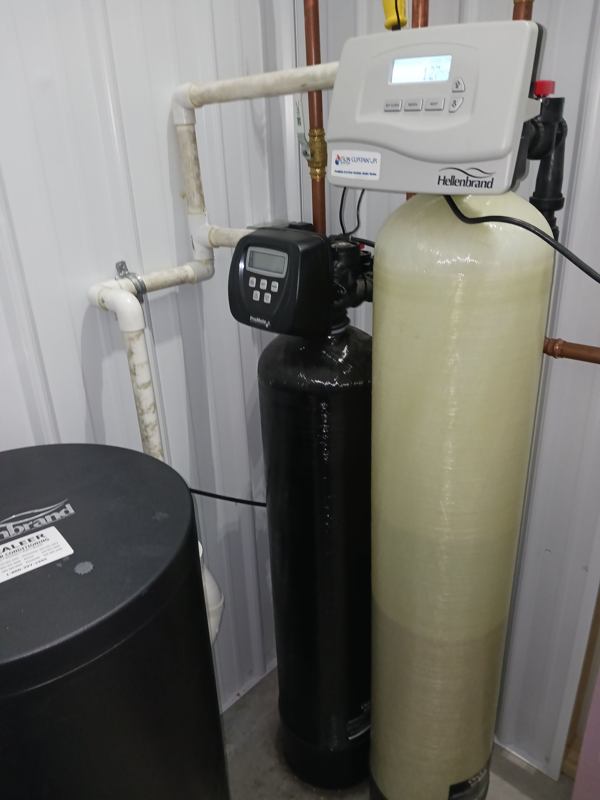 Water filtration system composed of a black and gray containers, inside a white room. Water filtration system composed of a black and gray containers, inside a white room.
