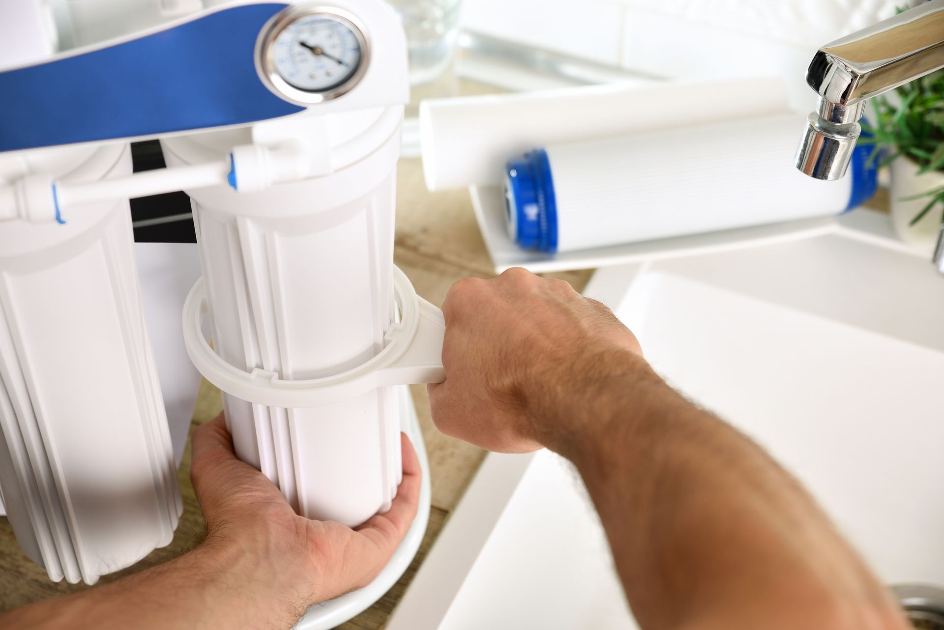 Plumber replacing filters for domestic reverse osmosis system near the sink.