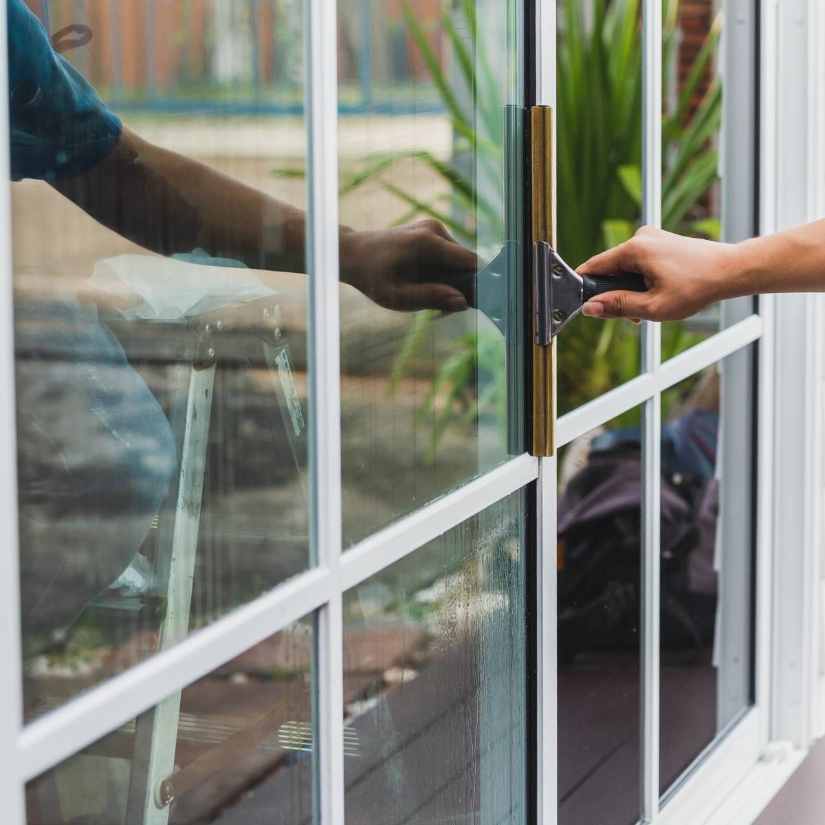 A person is cleaning a window with a spatula.