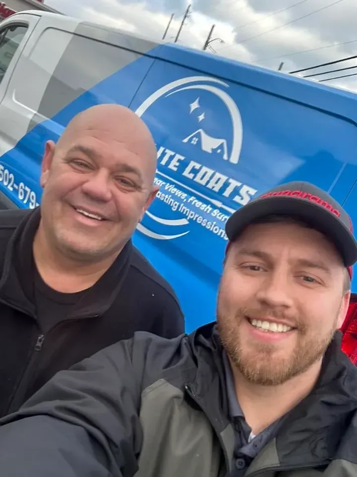 Two men are posing for a picture in front of a white coats van