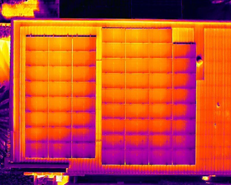 Thermal image of two large solar panels mounted side by side on a roof.