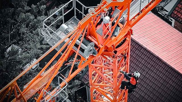 Construction workers on a orange crane with hardhat