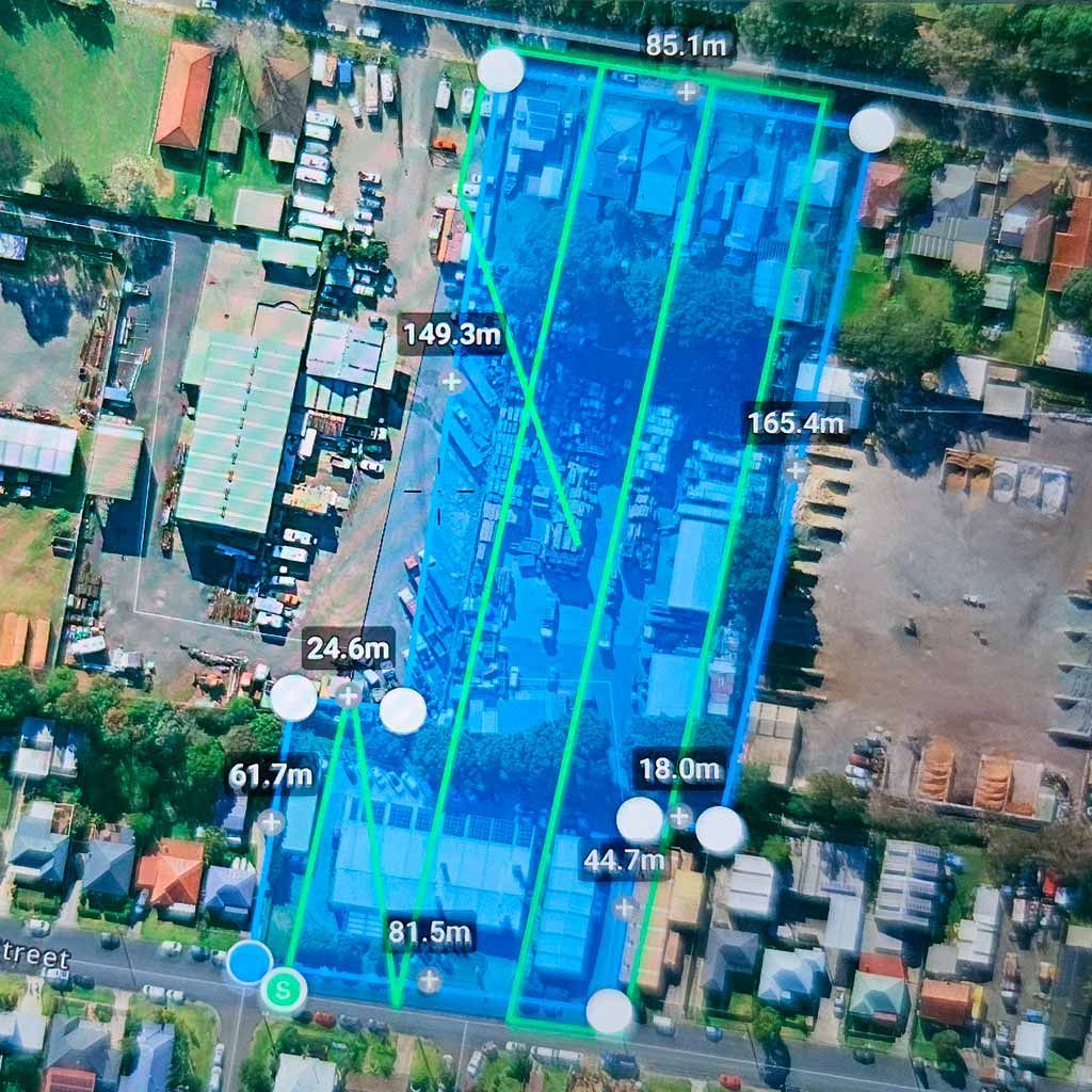 Satellite view of a long blue-highlighted property lot with measured boundaries in a dense neighborhood