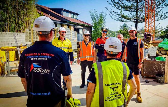 Our Crew on site in Bondi with Specialised Tradies Construction crew with drone pilots in hard hats and safety vests gathered at an outdoor worksite.