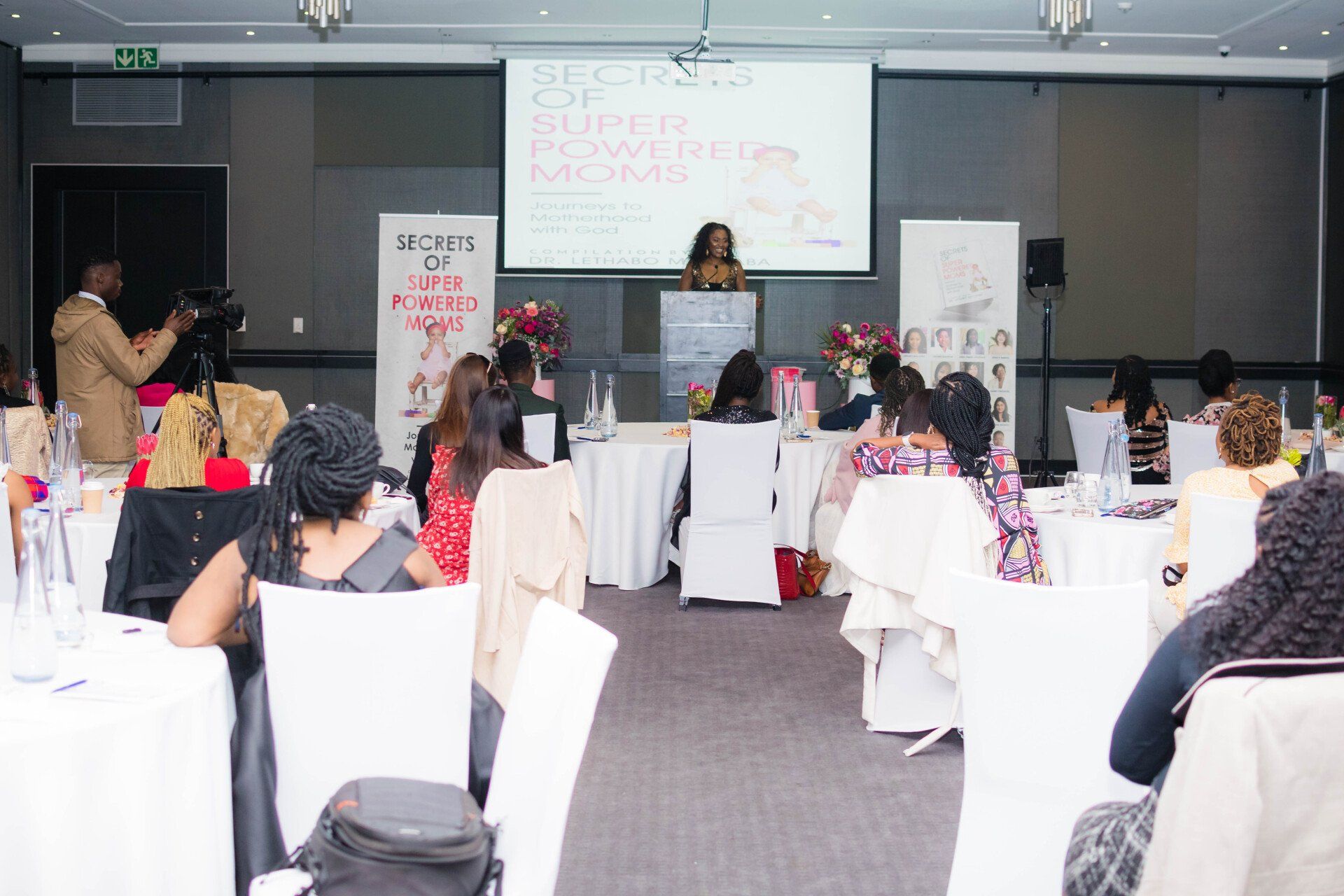 professional woman delivering a speech in front of woman seated at decorated tables
