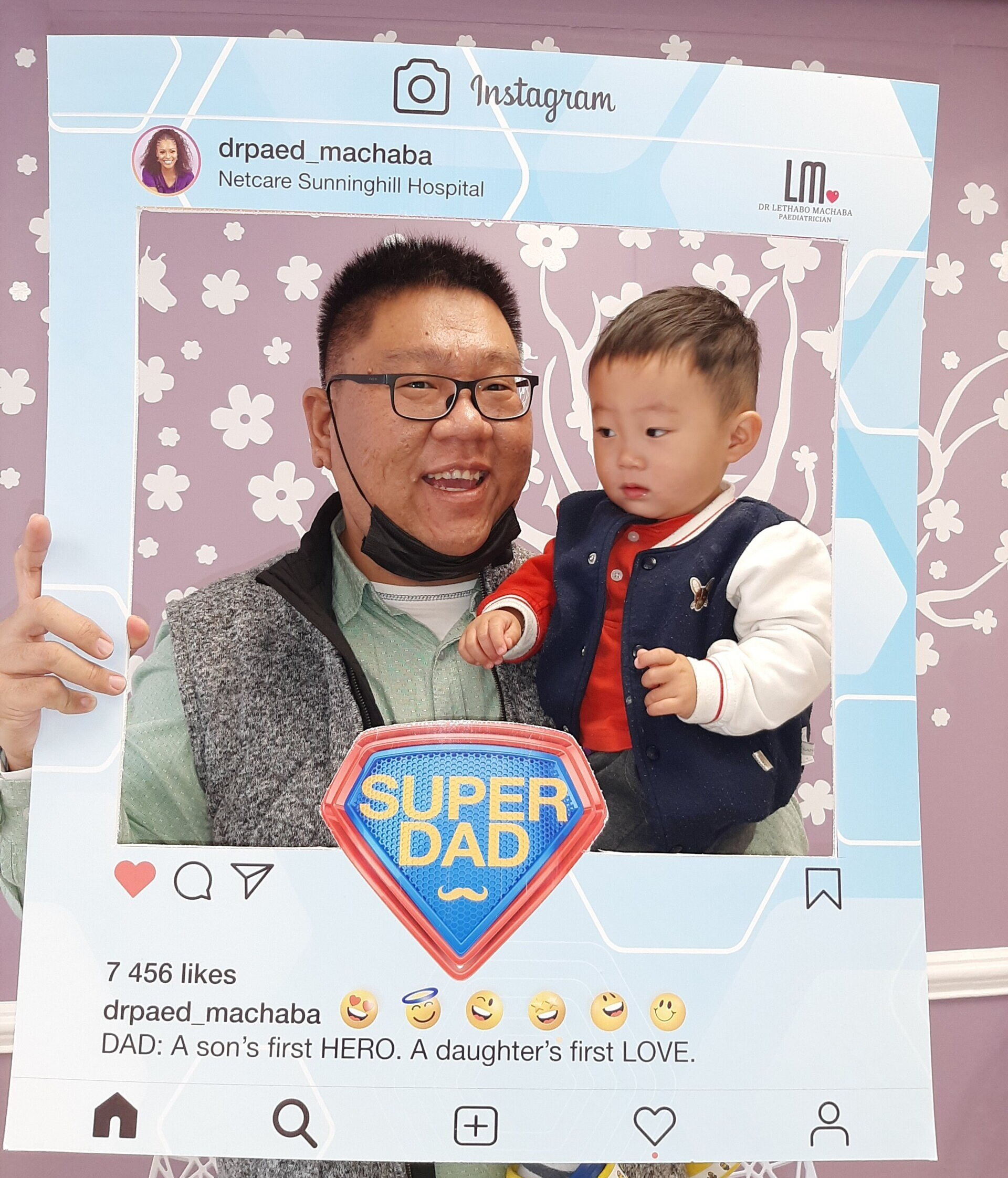 dad and toddler boy posing for a photo while holding an instagram frame