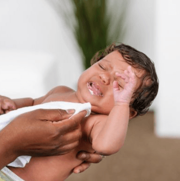 Baby with dirty mouth crying and mother wiping it's mouth