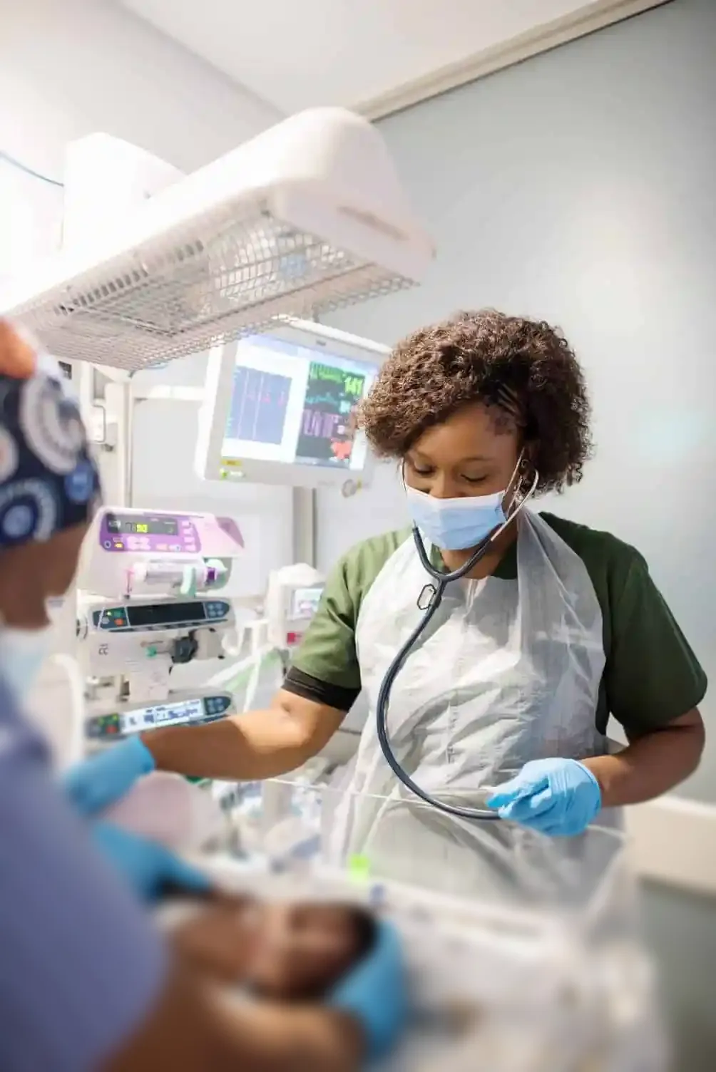 Doctor and nurse standing over newborn baby in an incubator
