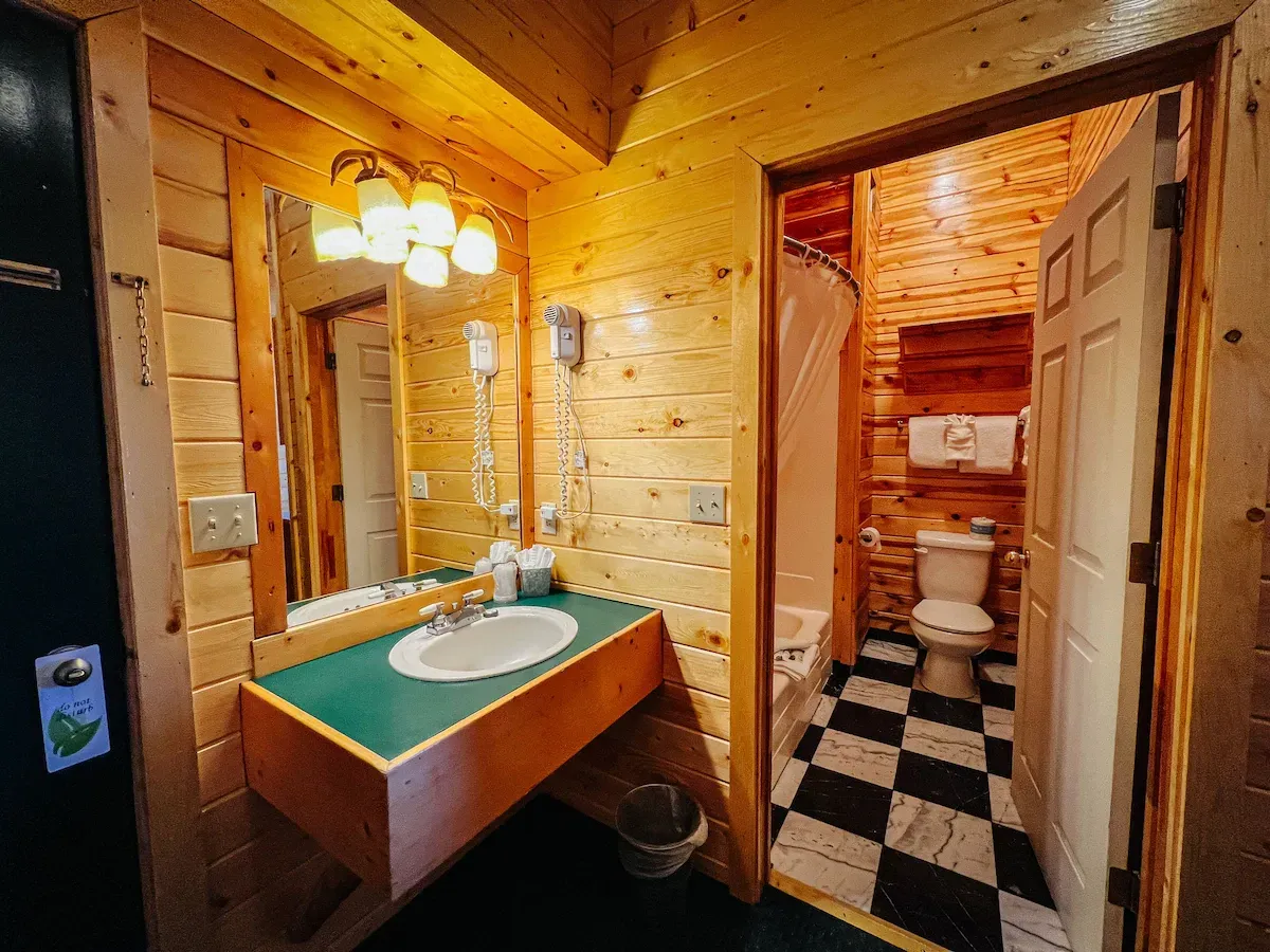 Bathroom with wooden walls and a black and white checkered floor; sink and toilet visible.