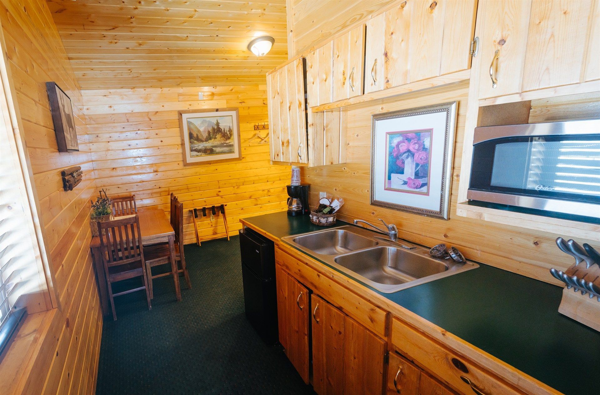 A kitchen with two sinks , a microwave , a table and chairs.
