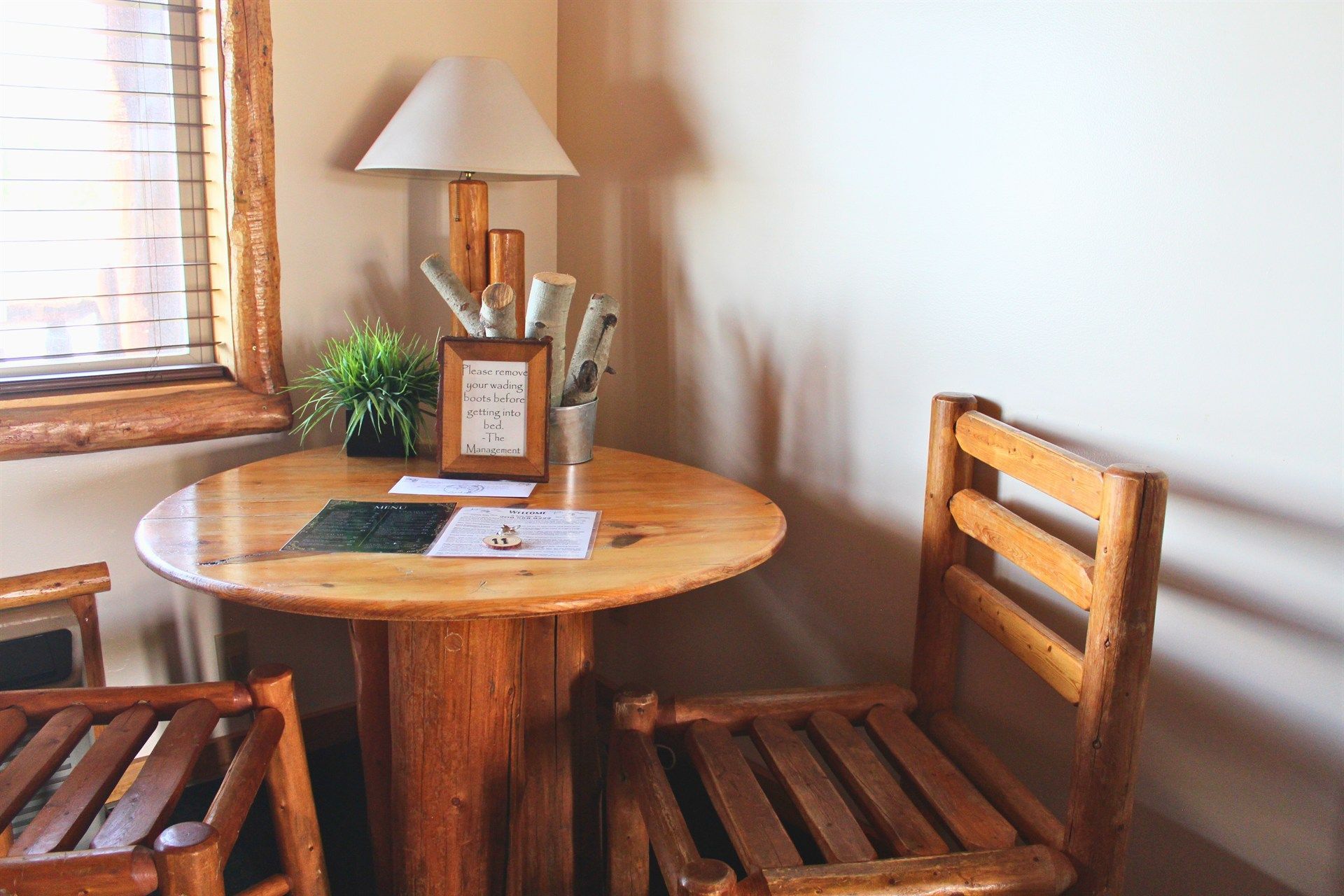 A wooden table with two chairs and a lamp in a room.