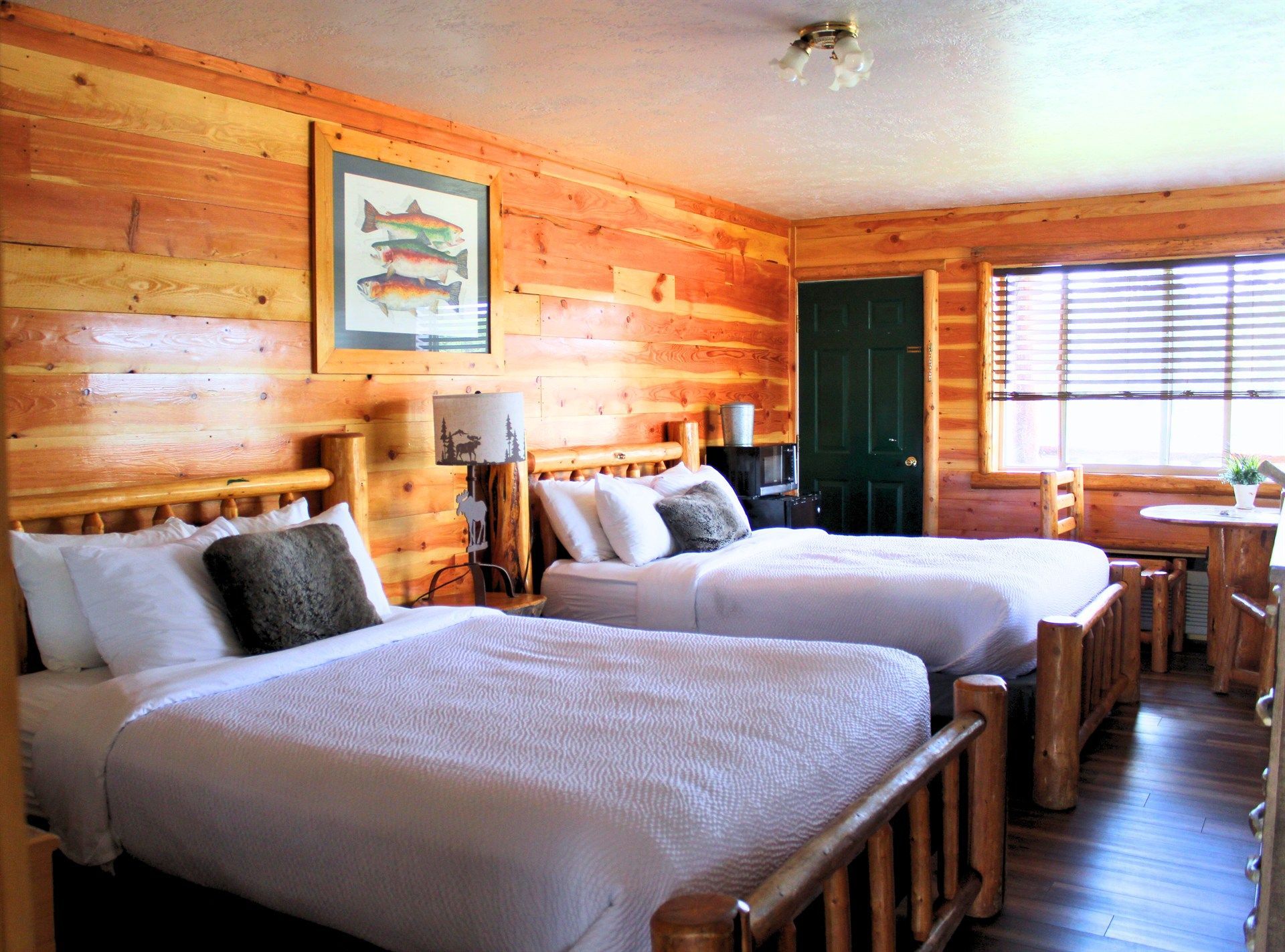 A hotel room with two beds and a picture of fish on the wall.
