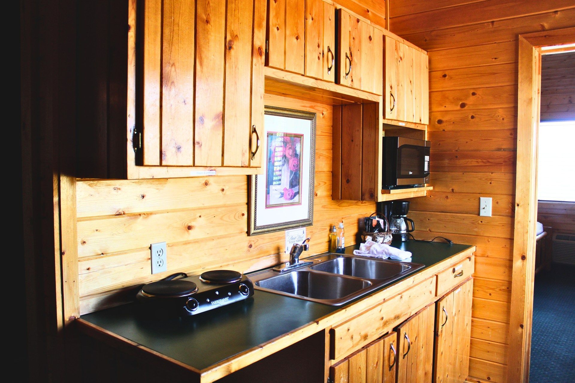 A kitchen with wooden cabinets and a sink and microwave