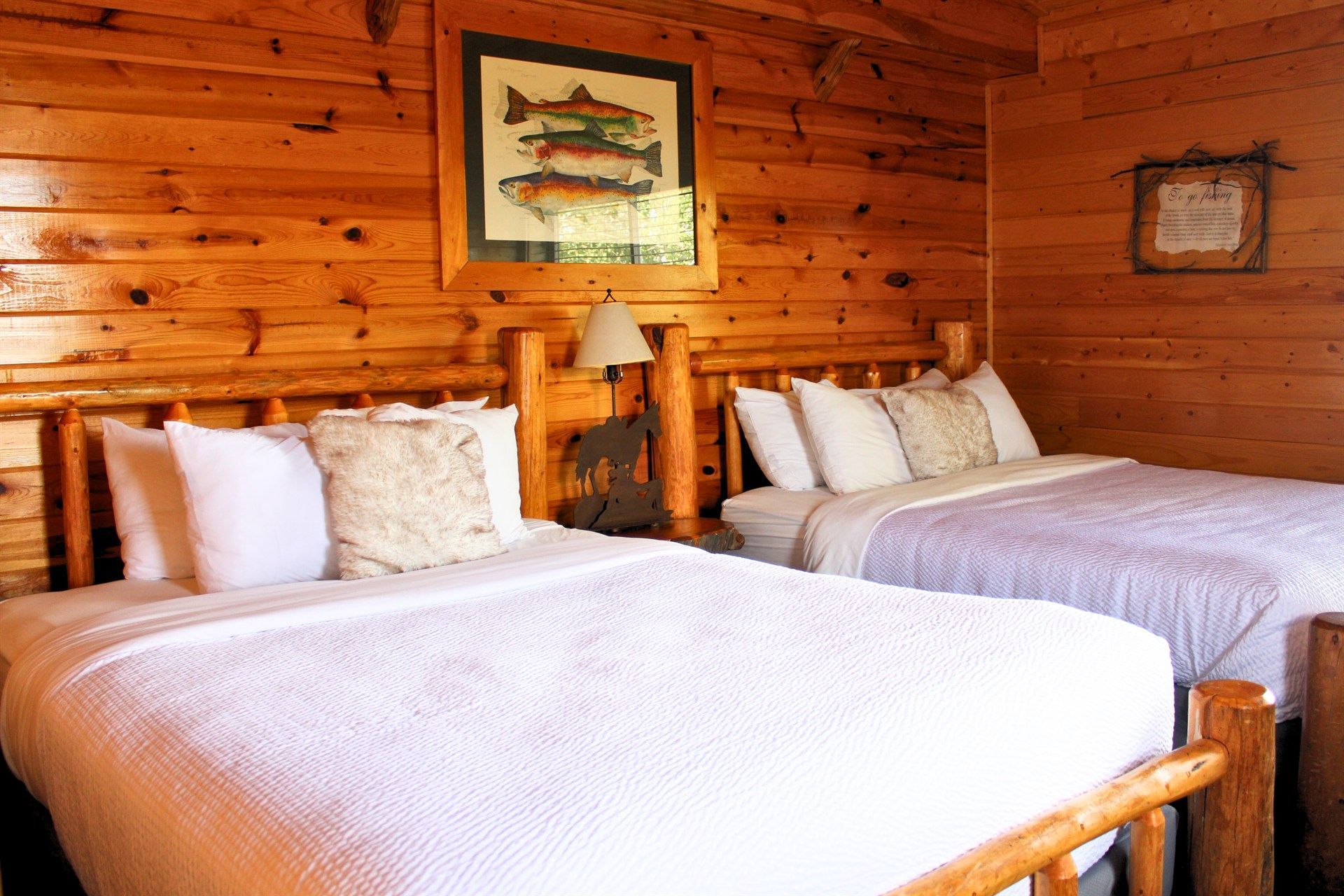 There are two beds in the room with a picture of fish on the wall.