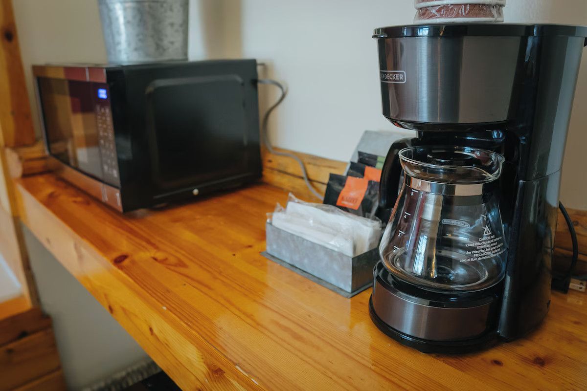 Coffee maker, microwave, and condiments on a wooden counter.