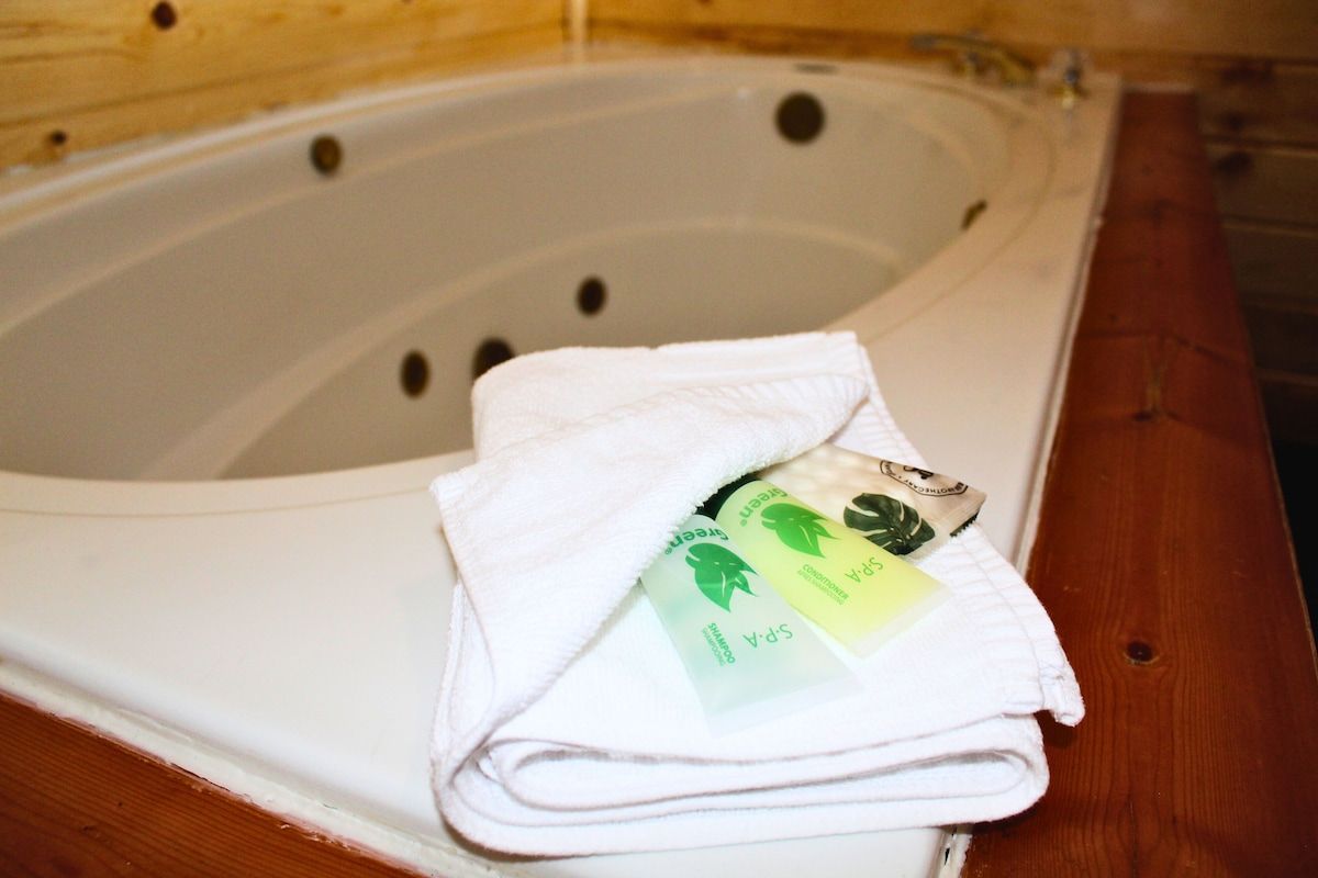 White jacuzzi tub with a folded white towel and small toiletries. Wooden trim surrounds.