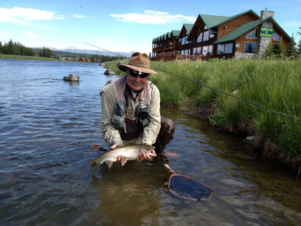 A man is kneeling in the water holding a fish
