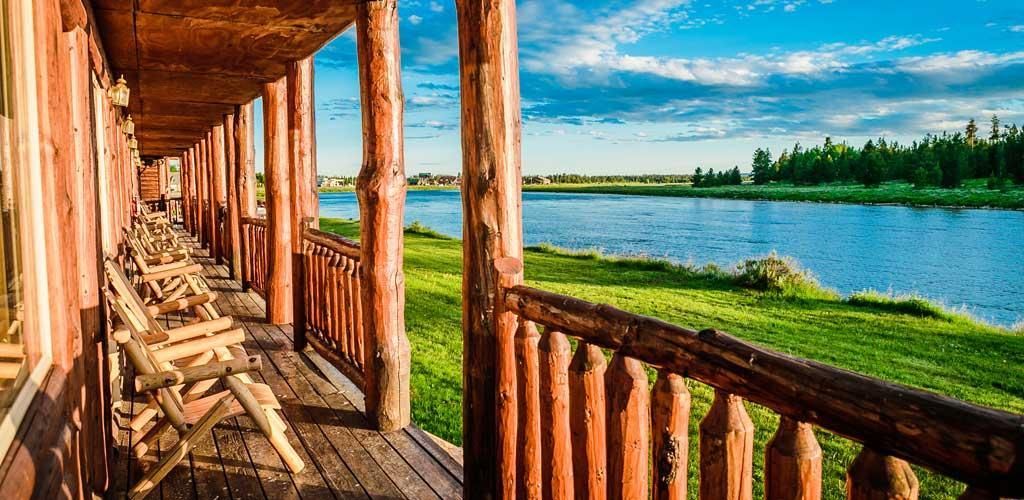 A wooden porch with chairs and a view of a lake.