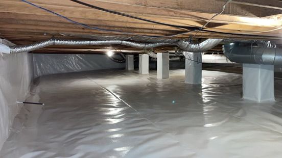 Crawlspace with plastic vapor barrier, support posts, and exposed insulation beneath floor joists