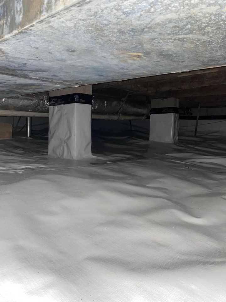 Snow-covered ground beneath a low concrete structure with wrapped support columns