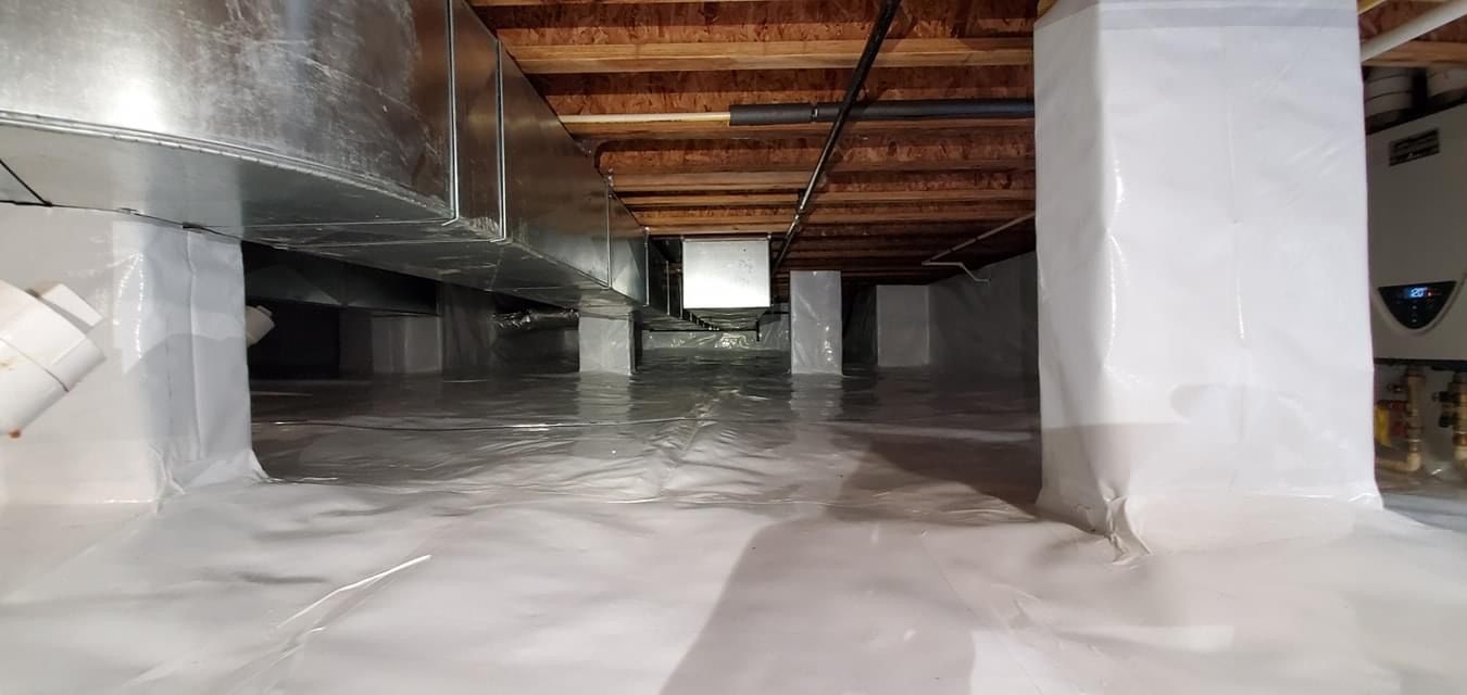 Flooded basement crawlspace with white insulation, exposed wooden joists, and support beams under the floor