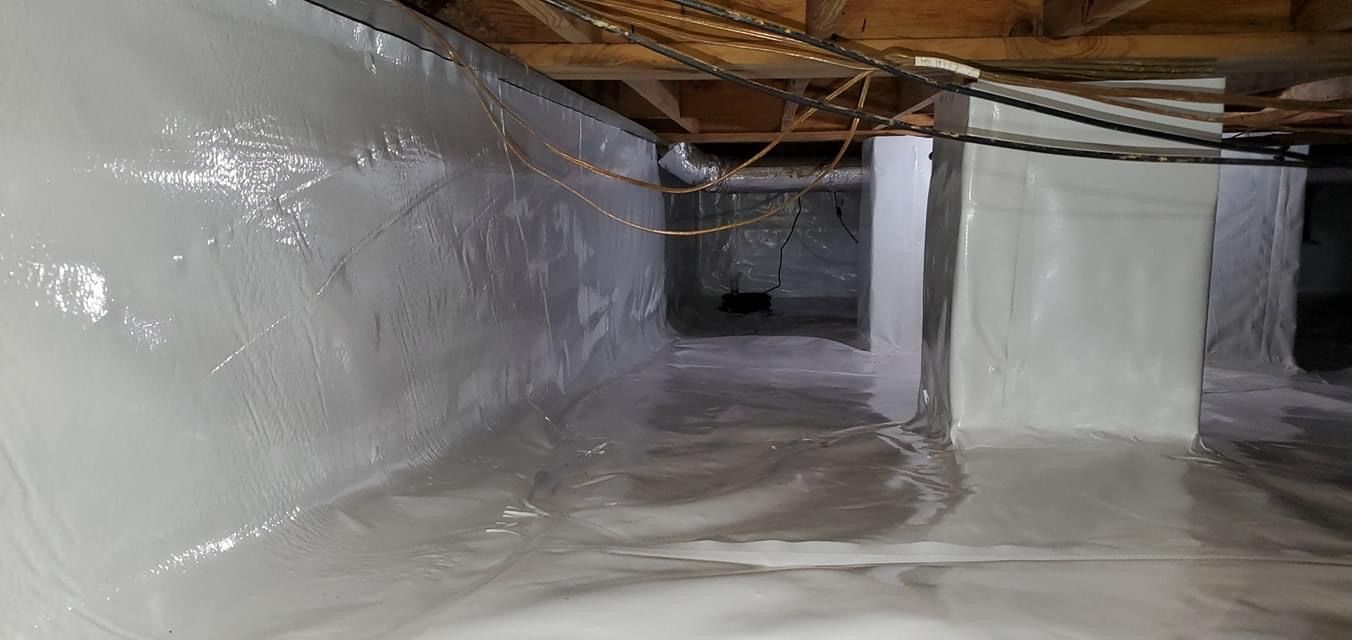 Plastic-lined crawlspace with exposed pipes and ductwork under a house