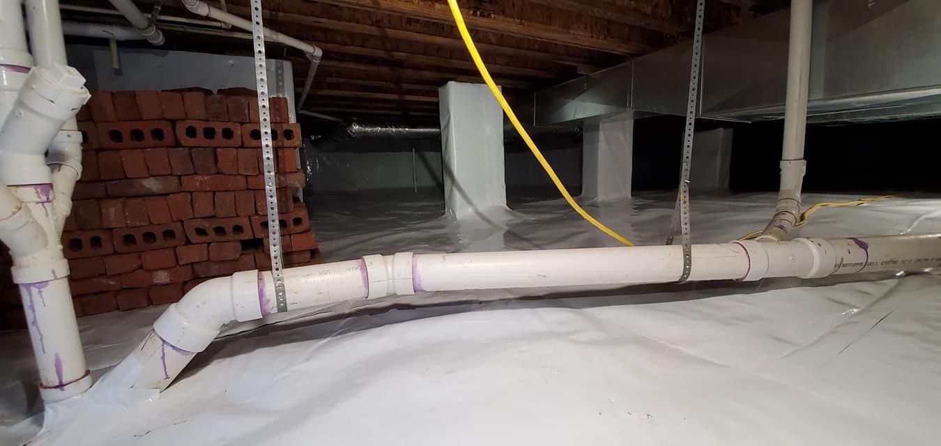 Attic crawlspace with white ducting, red brick stack, and exposed insulation under a sloped roof
