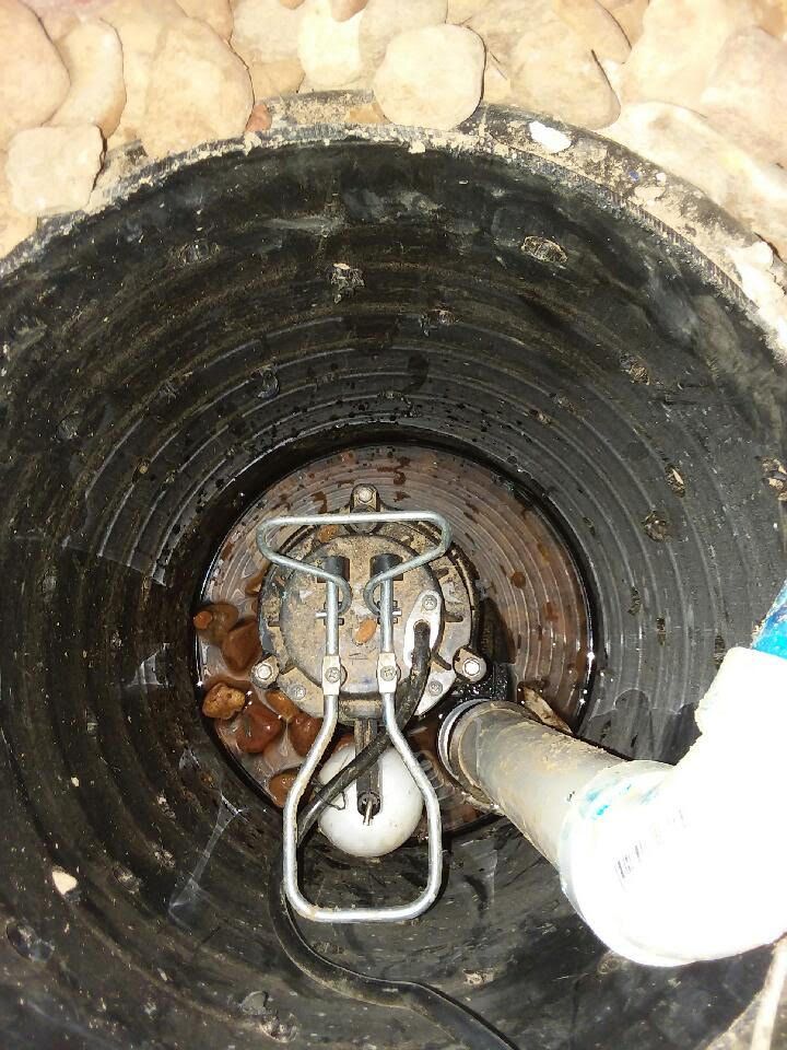 Interior of a circular concrete pipe with a white pipe and metal valve at the far end