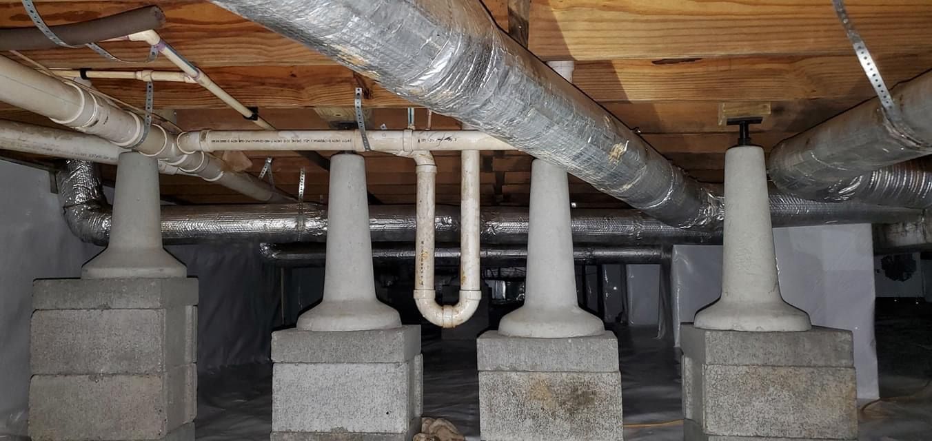 Crawlspace with concrete foundation piers and insulated ducts under a wooden floor