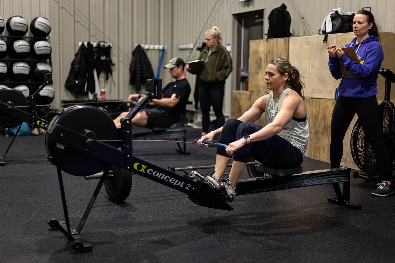 A group of people are sitting on rowing machines in a gym.