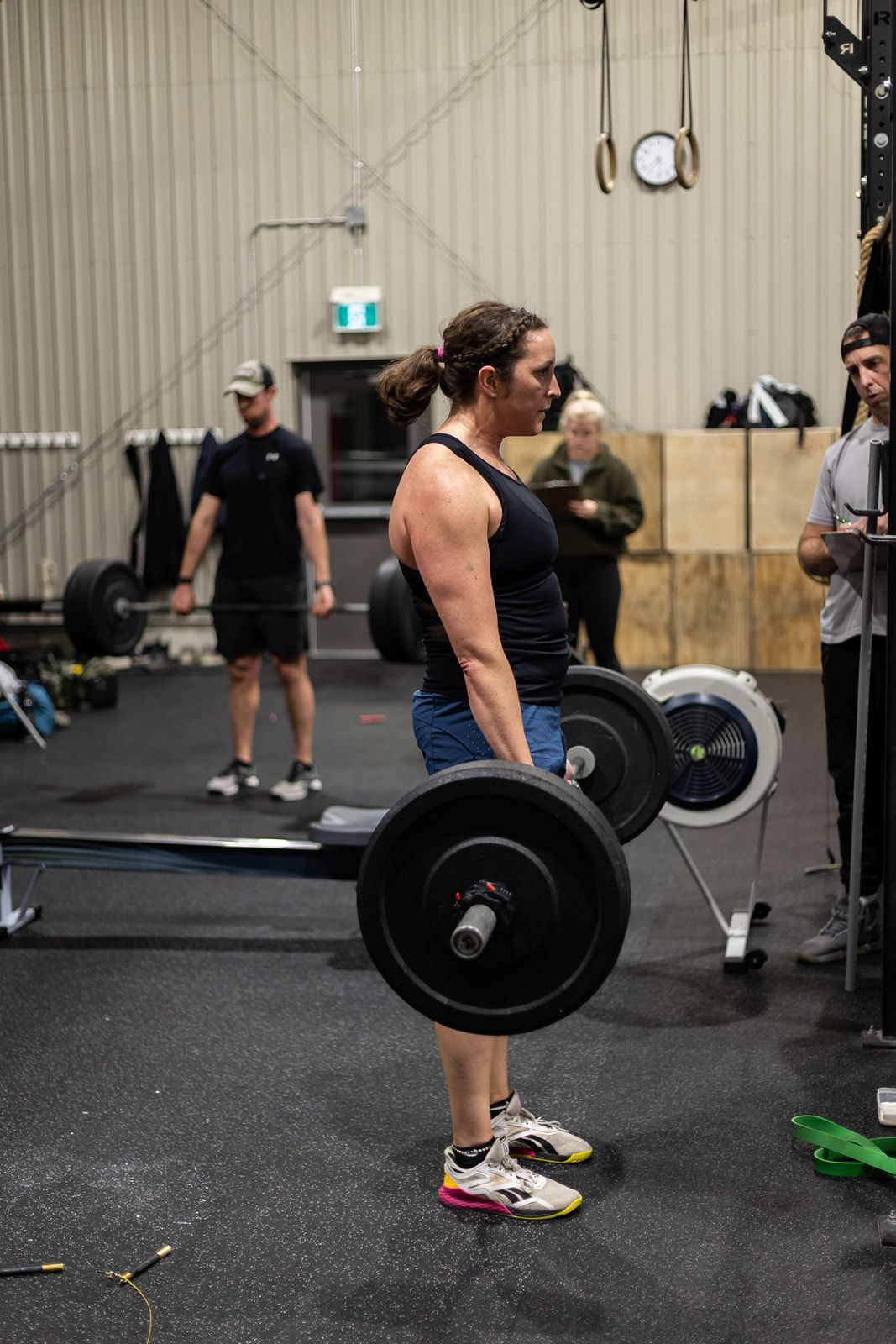 A woman is lifting a barbell in a gym.