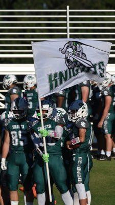 Football players in green uniforms, holding a white flag that says 