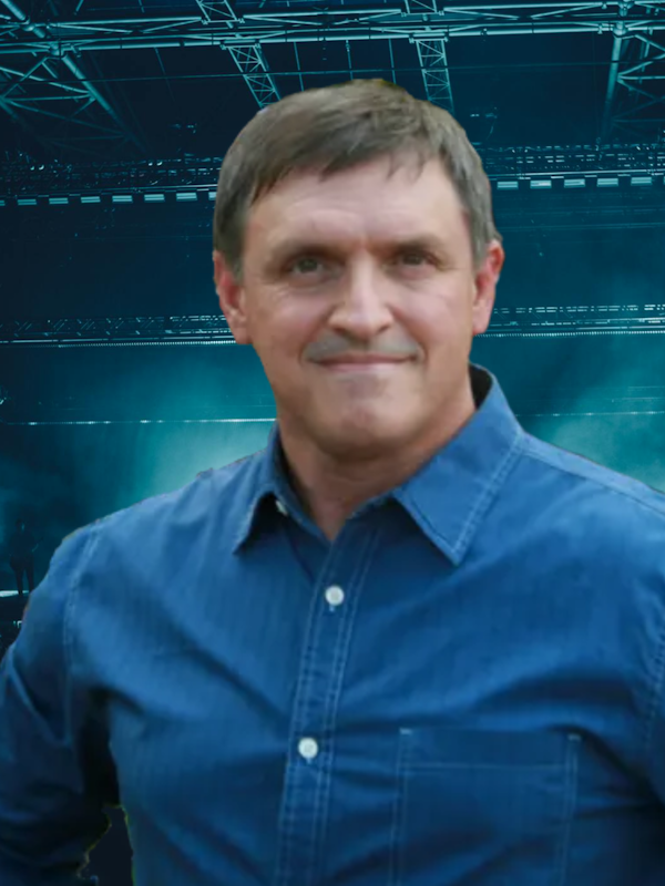 A man with a beard is standing in front of a black background.