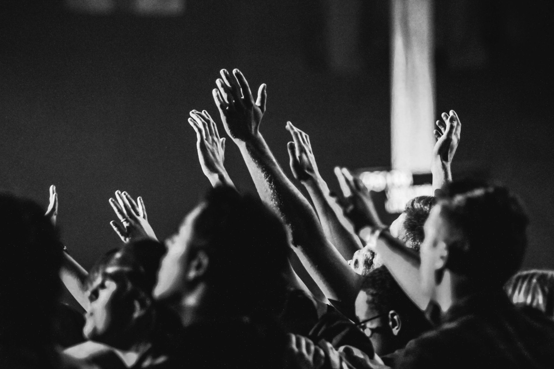 A crowd of people are raising their hands in the air at a concert.
