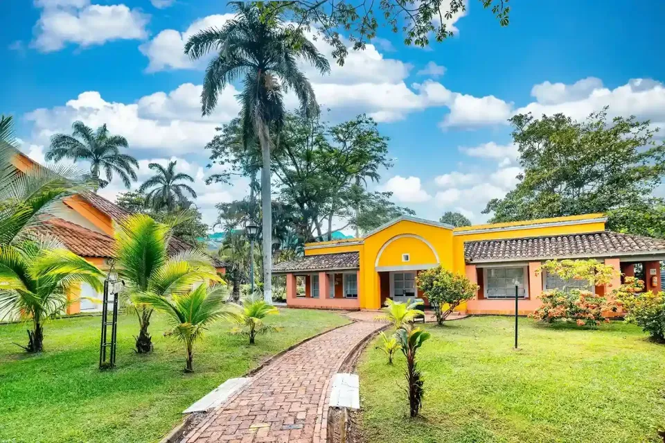 Fachada del Hotel Las Palmeras en Villeta, alojamiento campestre rodeado de palmeras y naturaleza.