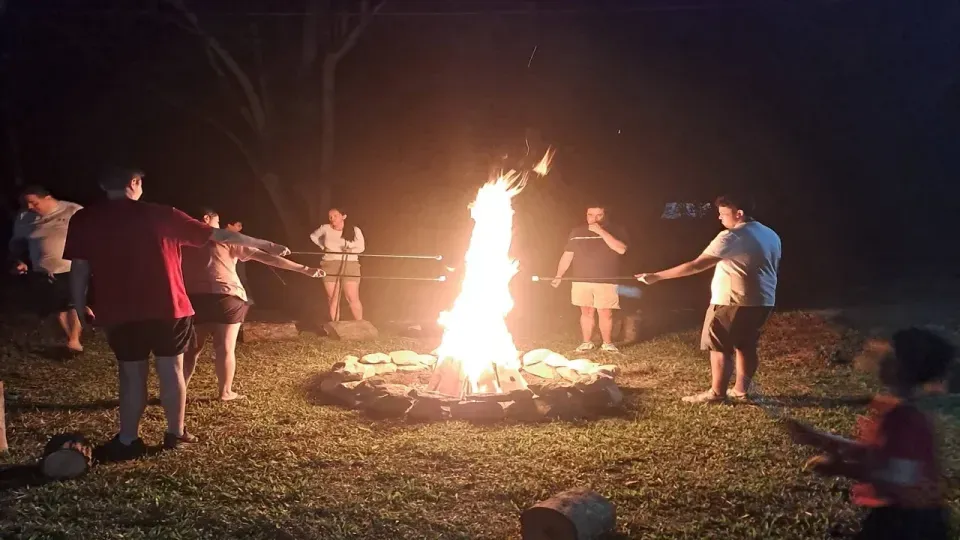Noche navideña en Villeta, familia compartiendo malvaviscos junto a la fogata en el Hotel Las Palmeras, ambiente cálido y campestre.