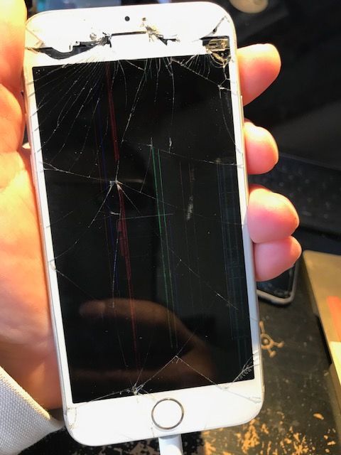 A person is holding a phone with a cracked screen