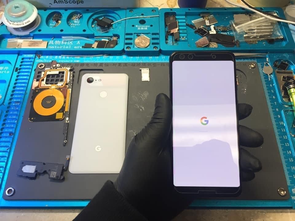 A person is holding a cell phone in front of a motherboard.