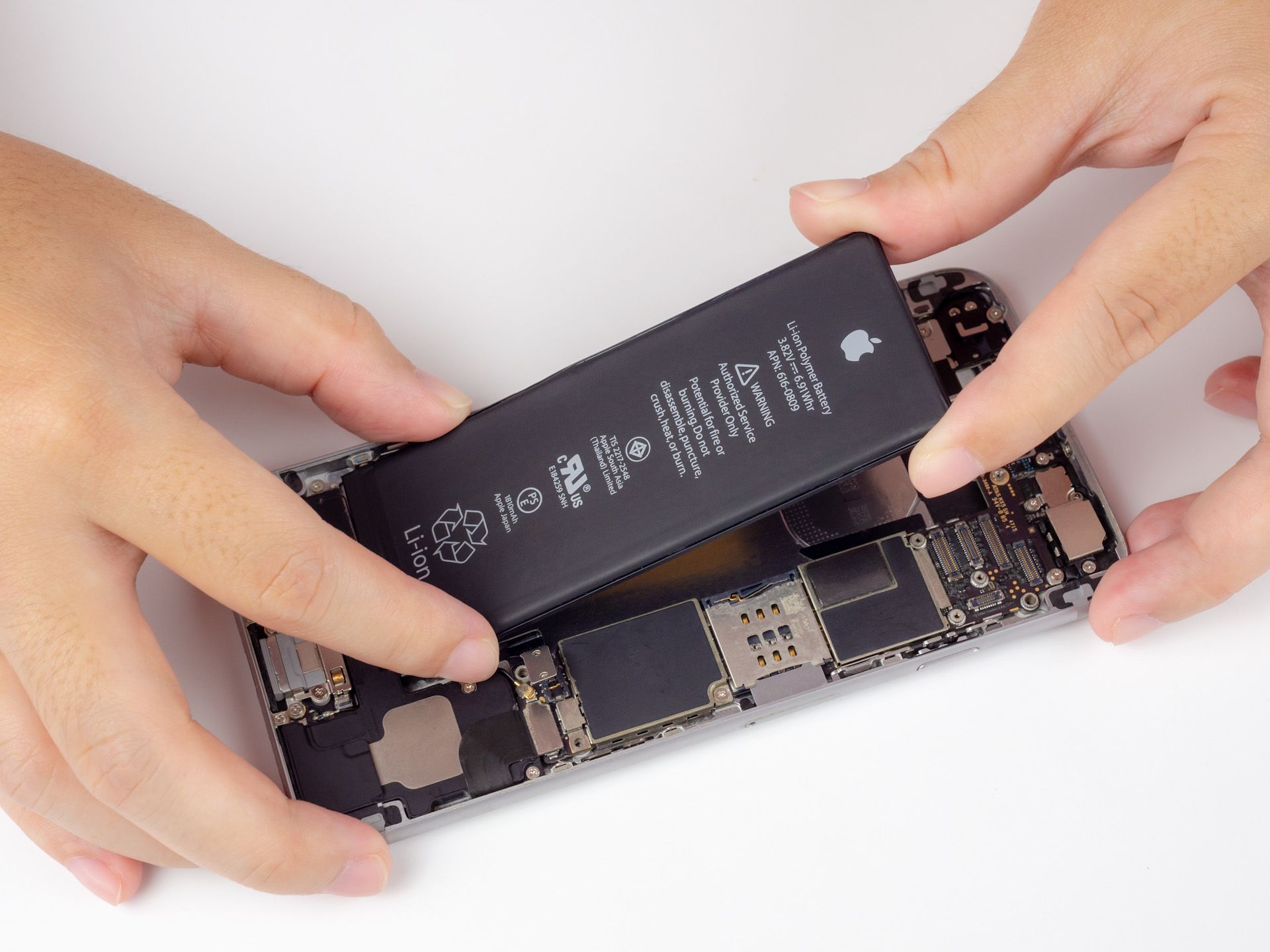 A person is removing a battery from an iPhone