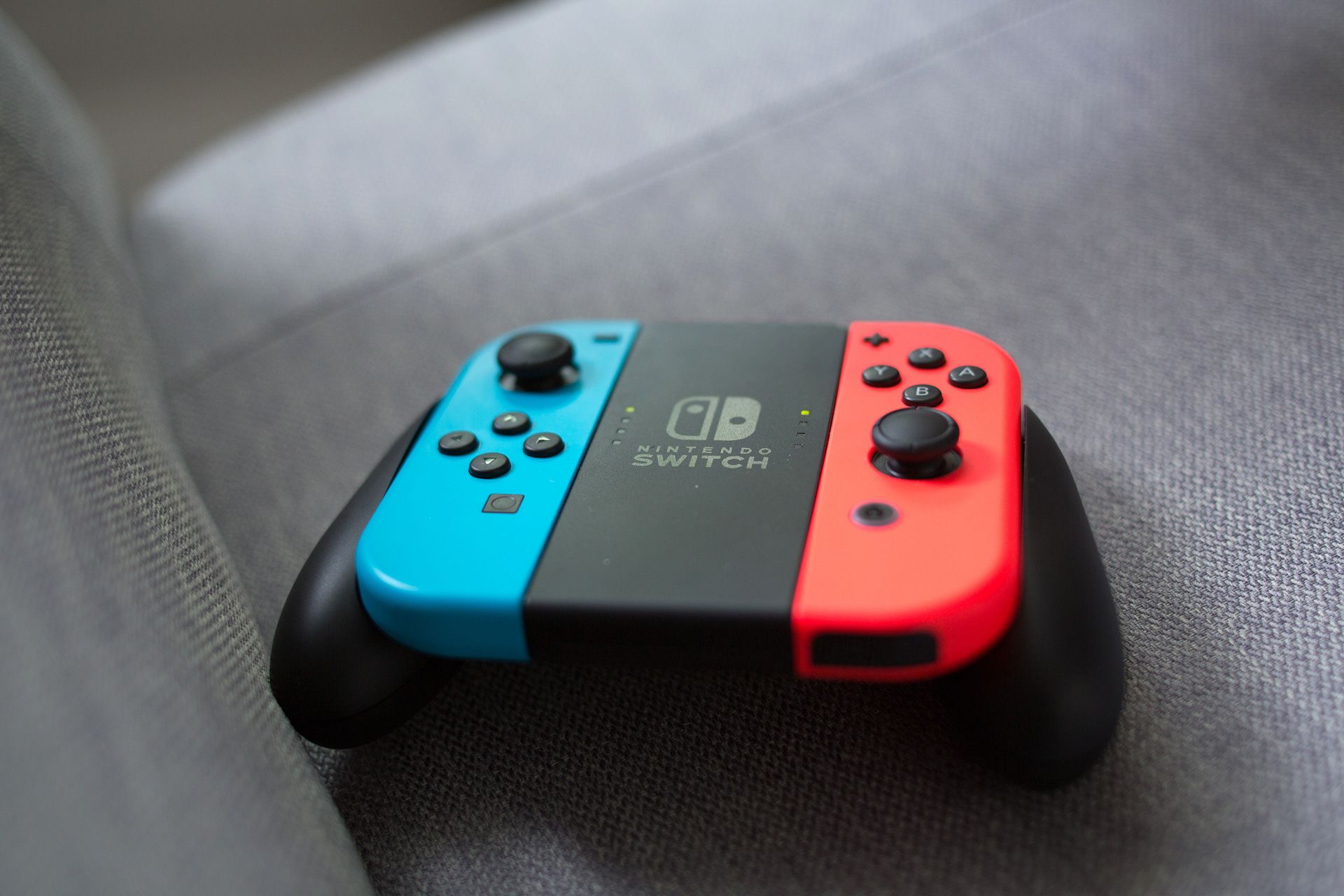 A red and blue Nintendo Switch controller is sitting on a couch.