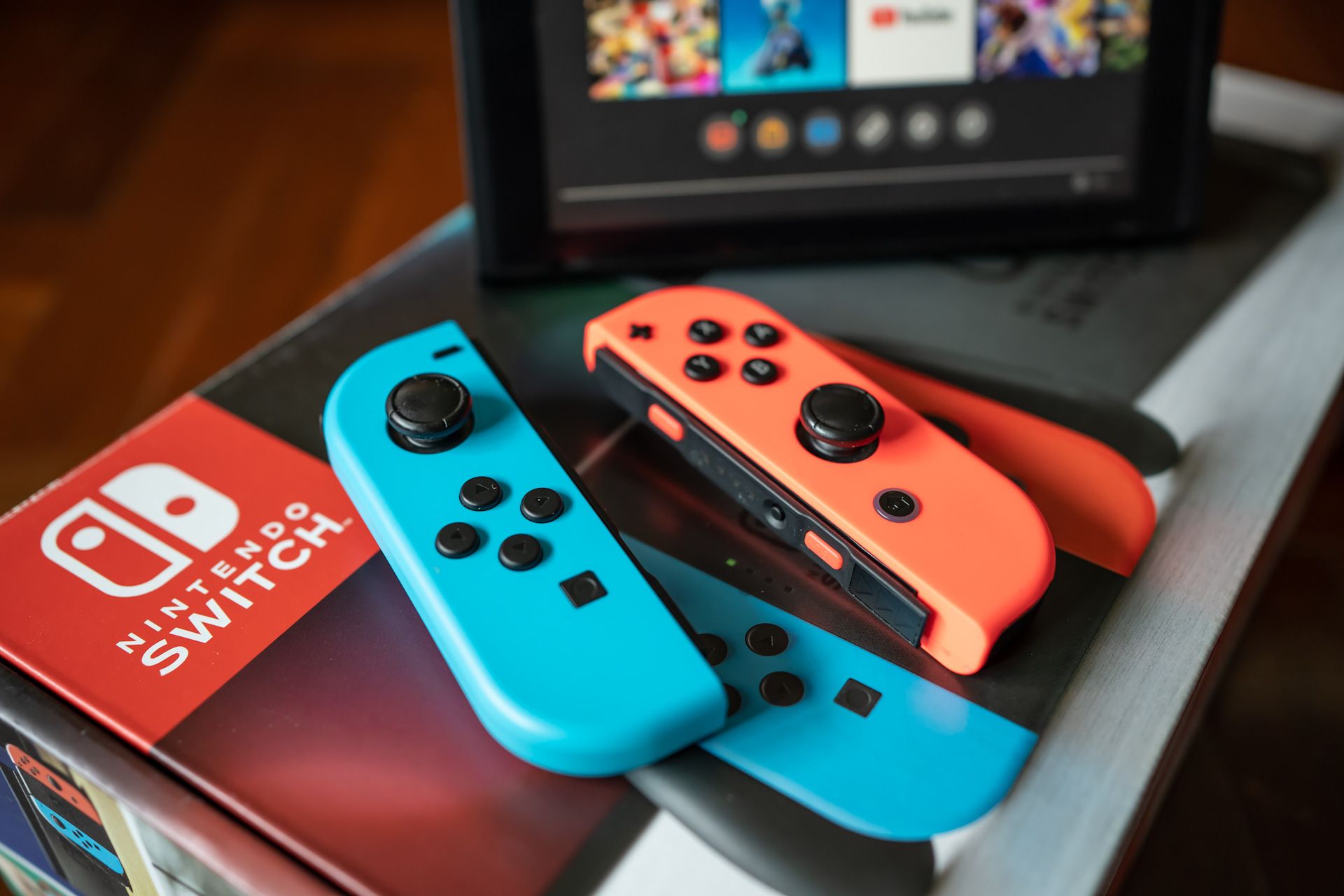 Two Nintendo Switch controllers are sitting on top of a Nintendo switch box.