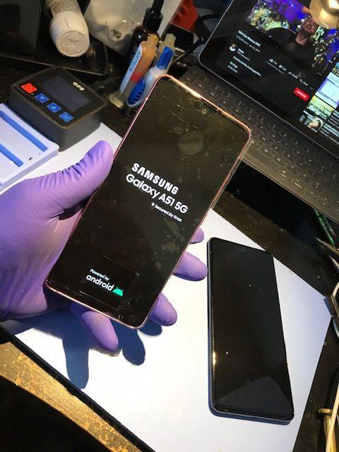 A person wearing purple gloves is holding a Samsung phone