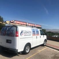 A white van with a ladder on top of it is parked in a parking lot.